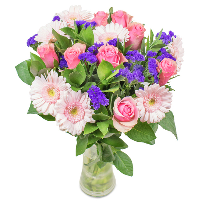 An elegantly curated bouquet presented in a pristine clear glass vase, this South Woodford arrangement is a harmonious blend of about 7 to 9 soft pink roses, each either quietly opening to reveal their full beauty or swirling with tightly furled grace. Intertwined with these classic florals are 5 to 7 pale pink gerbera daisies, their round, sunburst forms and almost-white centers drawing the eye. Accentuating this equilibrium, vibrant purple clusters-most likely statice or limonium-are scattered throughout, providing striking contrast and depth. The foundation of lush green foliage calls to mind the calming expanses of nearby Roding Valley Park, enhancing both visual freshness and charm. Water glistens in the transparent vase, underscoring the professional care and commitment to freshness that Florist South Woodford is known for. Detailed and thoughtfully arranged, this bouquet suits birthdays, anniversaries, Mother's Day, or as an inviting touch for a local business or home. Every stem is chosen with intent, echoing the neighbourhood's sense of warmth, celebration, and friendly spirit.